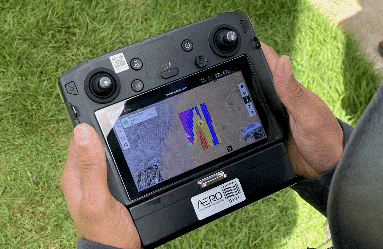 Pessoa segurando um controle de drone, visualizando um mapa com rotas de voo para monitoramento ambiental.
